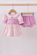 Baby girl's outfit with polka dot dress and pink bloomers on a hanger against a white background